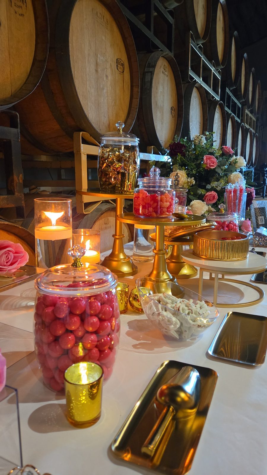 Full candy bar display along a wine barrel wall